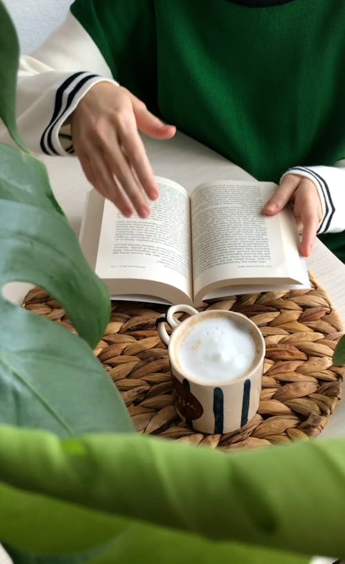 Person Drinking Coffee While Reading Book