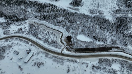 Aerial Footage of a Forest Road in a Snowy Landscape