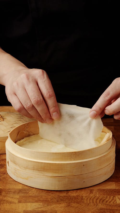Hands Ripping Slice of Food from Wooden Dish