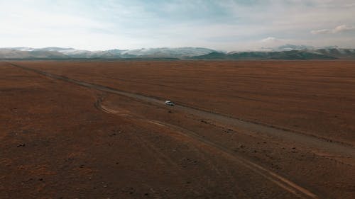 Drone Footage of a Car Driving on a Remote Desert Road 