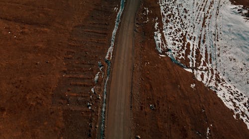 A Car Driving on a Dirt Road in a Snowy Landscape 