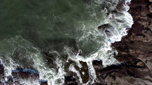 Top View of Waves Crashing on a Rocky Shore
