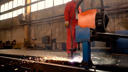 A Man Operating a Plasma Cutting Machine at a Factory