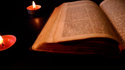 An Old Book Beside the Candles