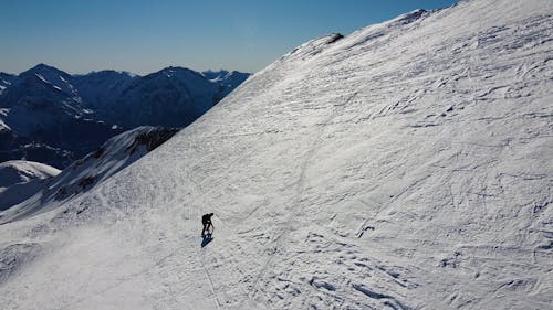 Drone Footage of a Person Climbing a Snow Covered Mountain 