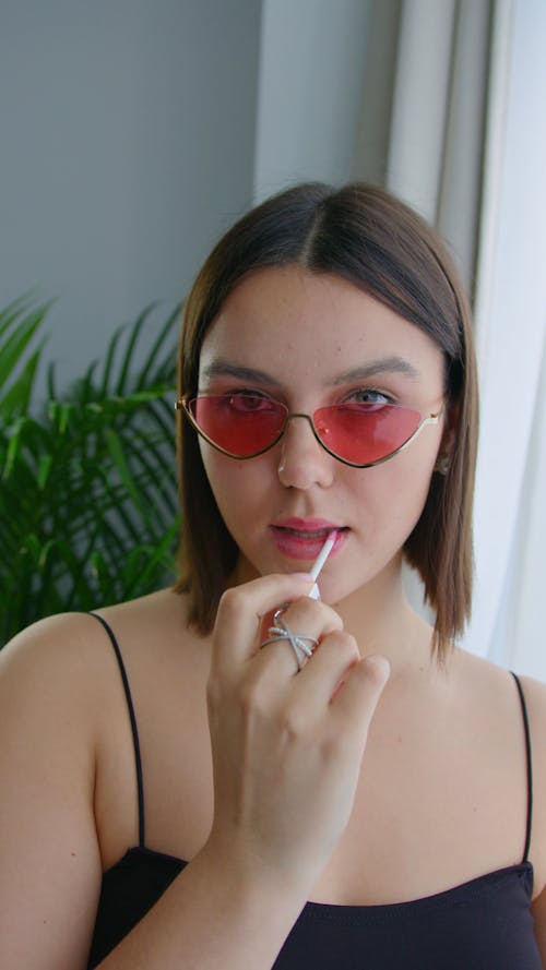 A Young Woman Posing while Applying Lip Gloss 