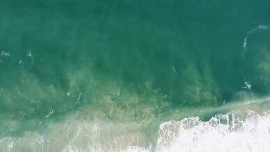 top view of breaking waves on a sandy beach
