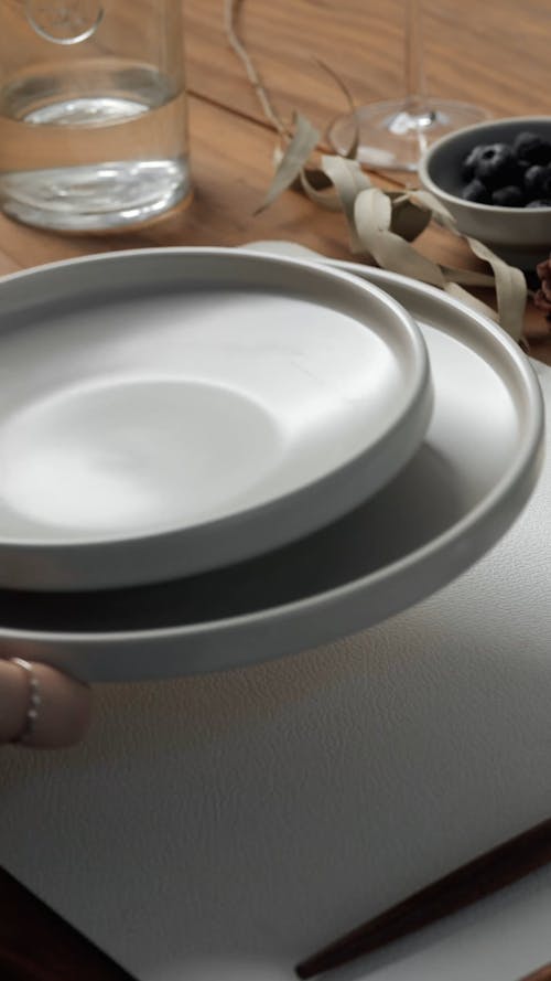 Hand Placing Plates on a Table
