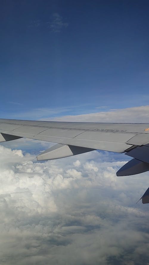 View of Clouds and a Wing from a Flying Airplane