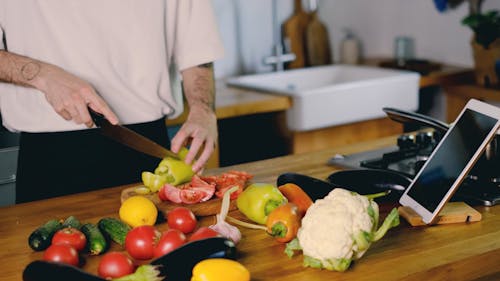 A Person Slicing Fresh Vegetables with a Kitchen Knife 