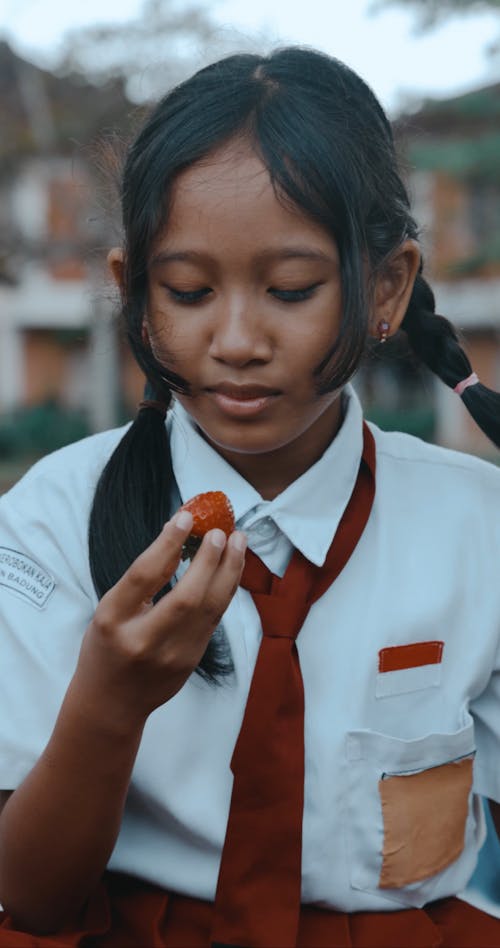 Schoolgirl in a Uniform Eating a Strawberry