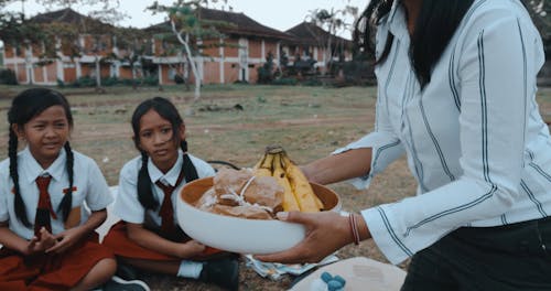 Teacher Giving Food to Schoolchildren at a Field Trip Picnic