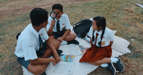 Children Having Fun Playing with a Magnifying Glass at a Field Trip