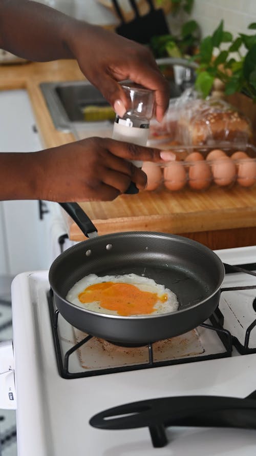 Person Making a Fried Egg in the Kitchen