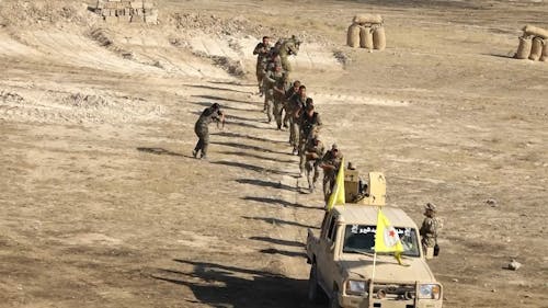 Group of Soldiers Following a Military Car in a Desert