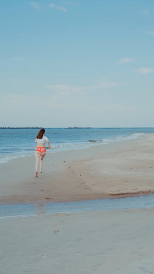 Woman Running on a Beach in Lifeguard Shorts