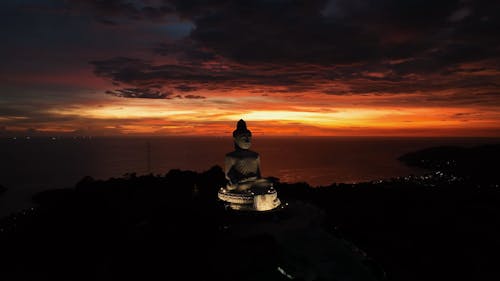 Drone Video of a Buddha Statue under a Dramatic Orange Sky