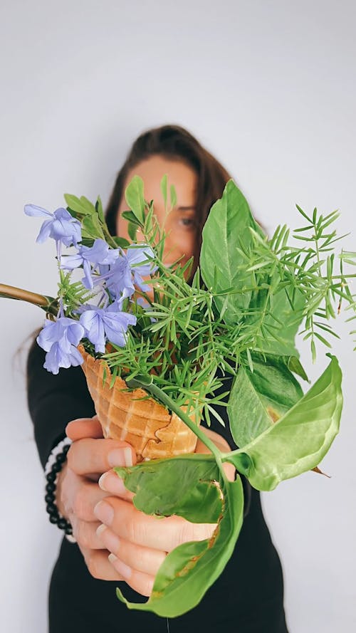 Close-up View of Woman Holding Plants in Cone