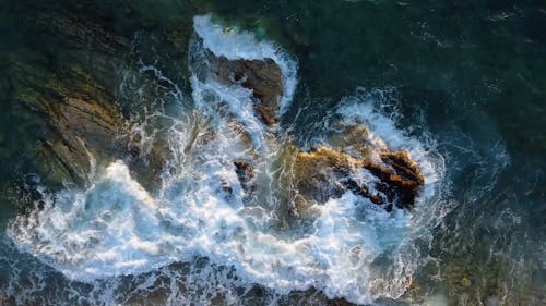 Top View of Waves Crashing on Rock Formations 