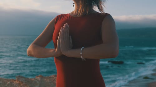 A Woman Practising Yoga on a Rock by the Sea