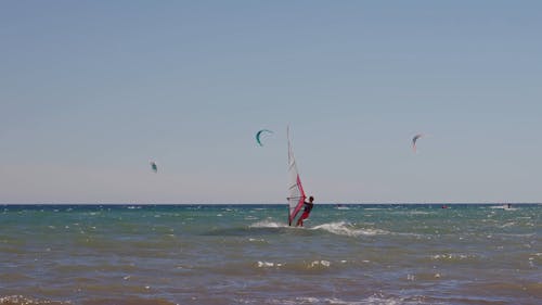 People Windsurfing and Kitesurfing in the Sea 