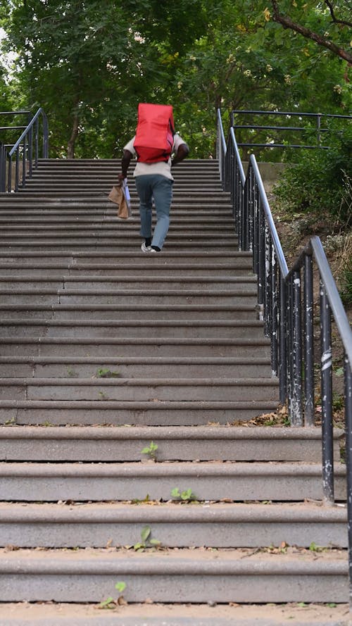 A Man Walking while Going Up on Concrete Stairs