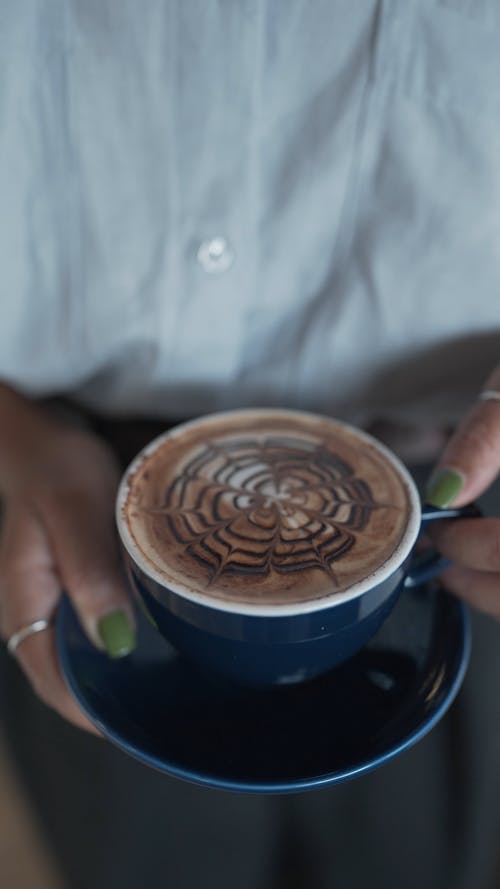 A Person Holding a Cup of Coffee with Latte Art