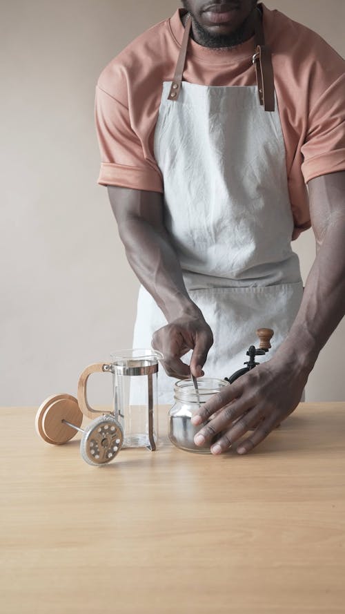 A Man Putting Fresh Ground Coffee into a French Press