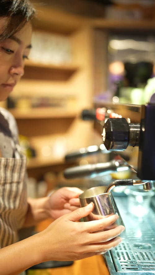 A Barista Frothing Milk on an Espresso Machine 