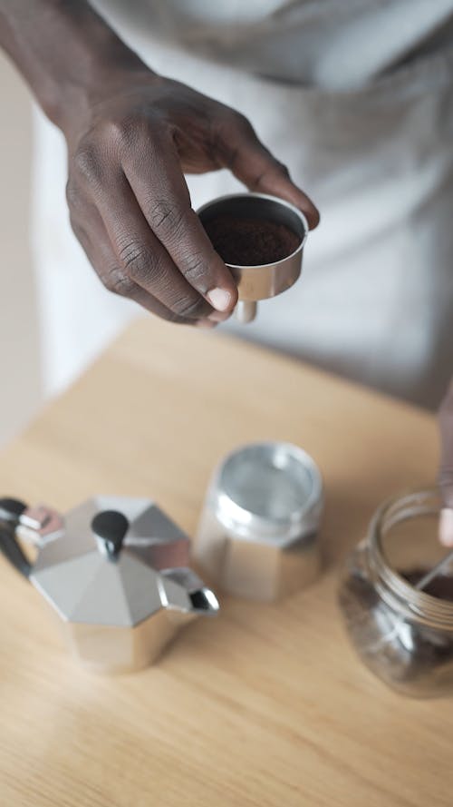 Person Filling the Funnel of Moka Pot with Ground Coffee