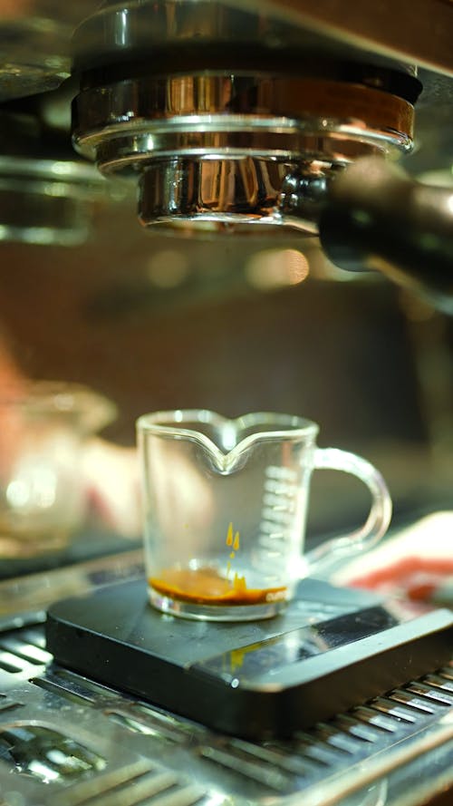 An Espresso Machine Pouring Coffee into a Glass Cup 