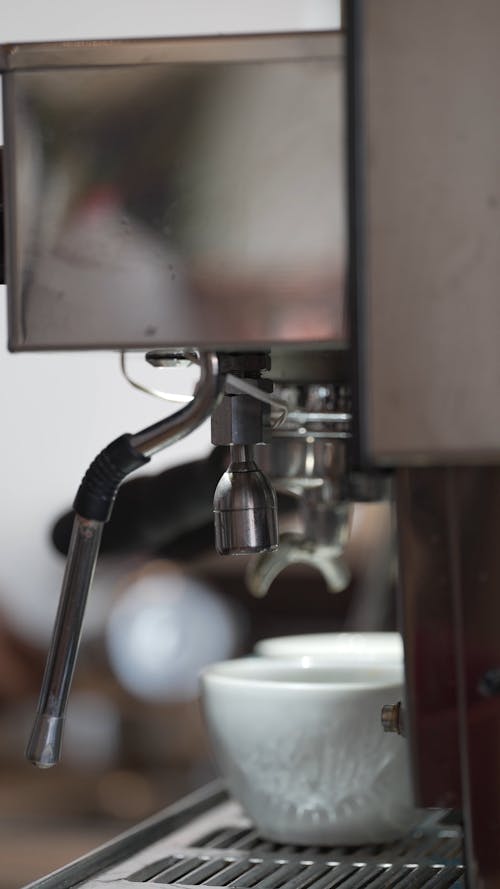 An Espresso Machine Pouring Coffee into a Ceramic Cup 