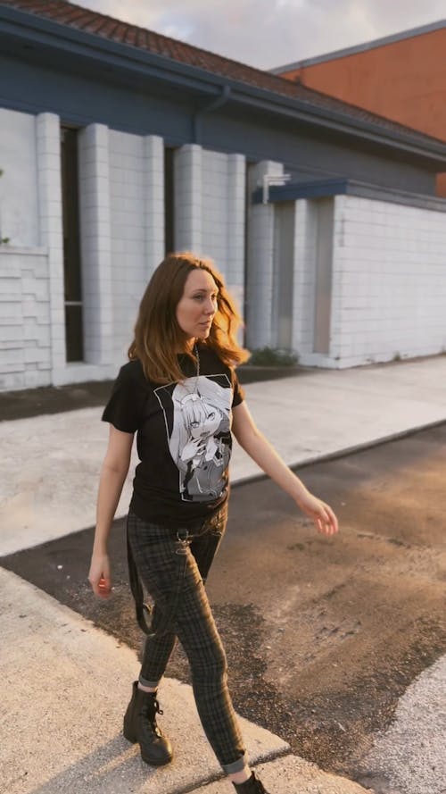 A Young Woman Crossing a Cobblestone Street at Sunset 