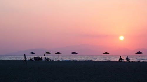 Silhouettes of People at the Beach under a Colorful Sunset Sky