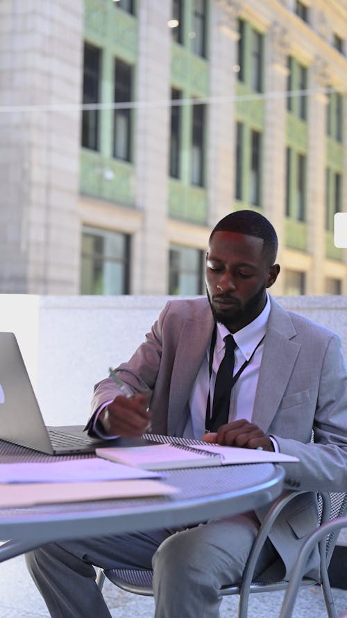 A Businessman Using his Laptop and Taking Notes