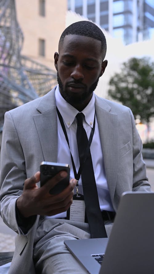 A Businessman Checking his Phone while Working on his Laptop 