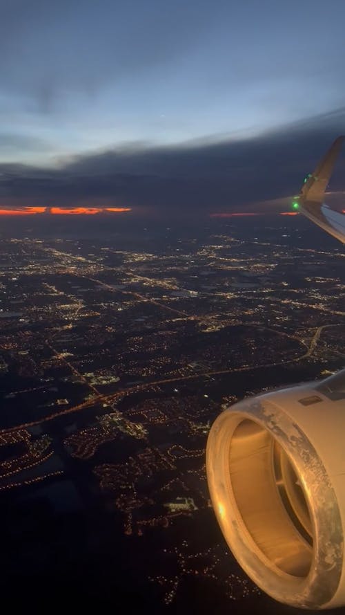 Window View from an Airplane Flying over a City at Dawn