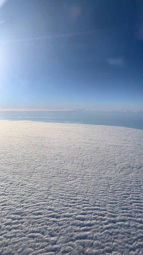 View from an Plane Window Flying above a Layer of Clouds