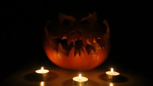 Burning Candles and a Spooky Halloween Pumpkin