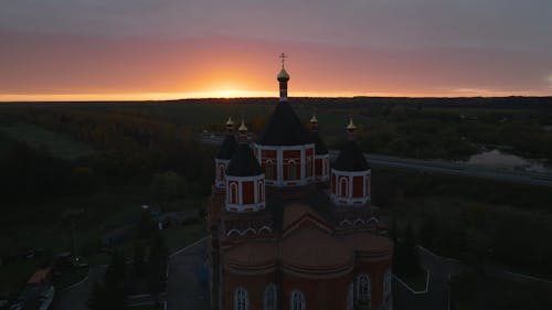 Drone Footage of a Church by a Road under a Sunset Sky
