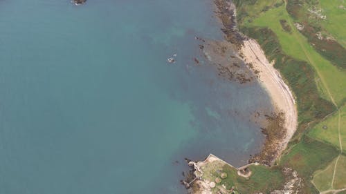 Drone View of a Cliffed Coastline and Green Fields