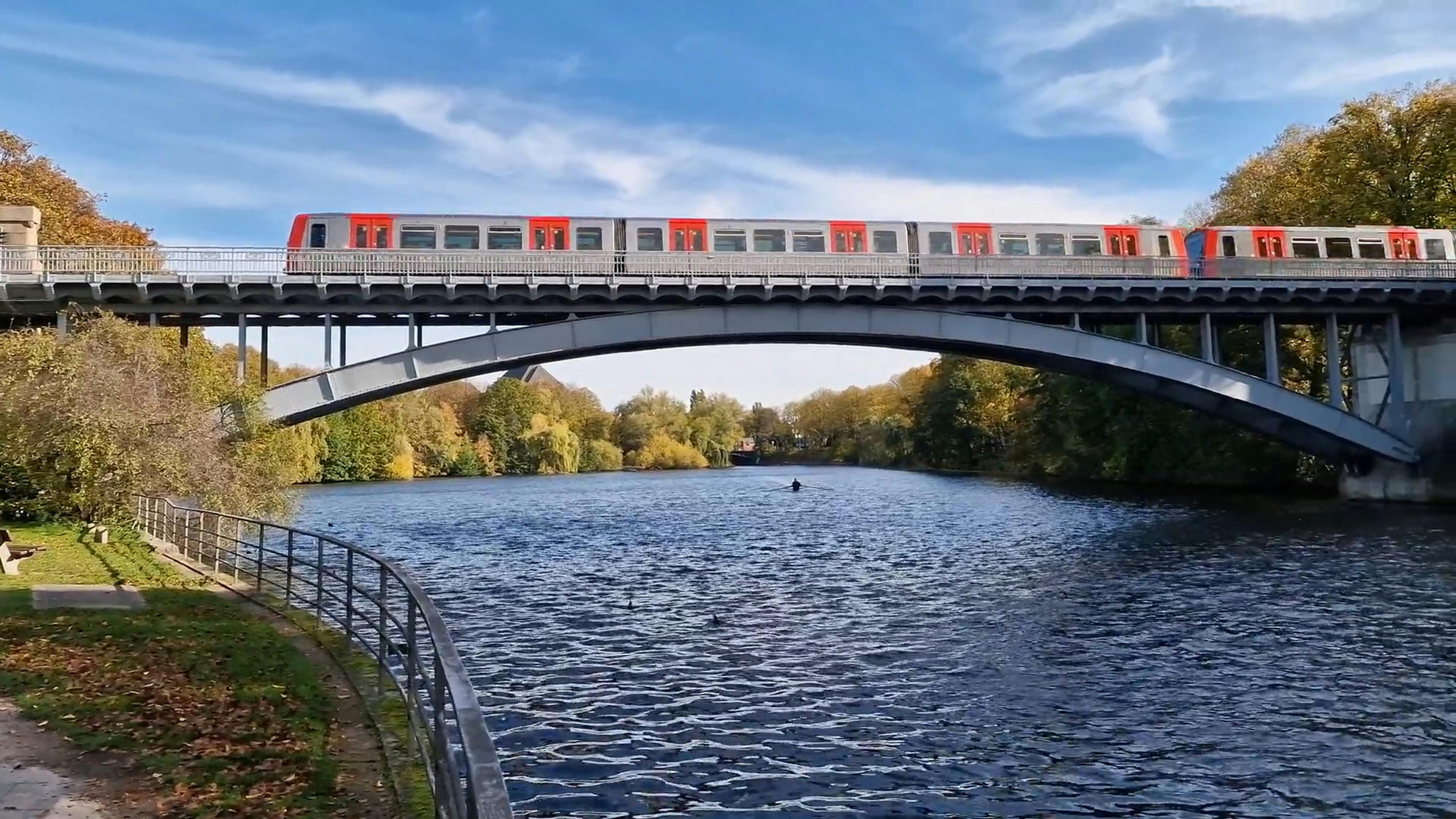 Train Passing on Bridge on River and People Canoeing near Ducks Free