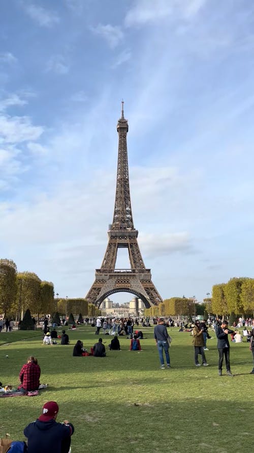 People Relaxing and Taking Photos of the Eiffel Tower in Champ de Mars