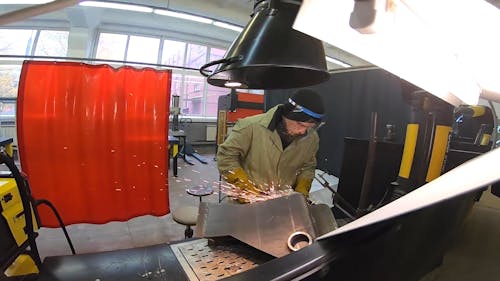 A Man Using an Angle Grinder on a Metal Piece 