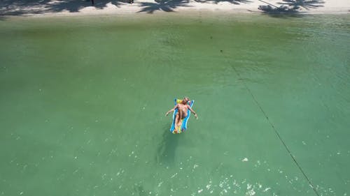 Woman on Mattress on Ocean Shore