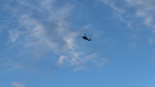 A Helicopter Flying Under the Blue Sky and White Clouds