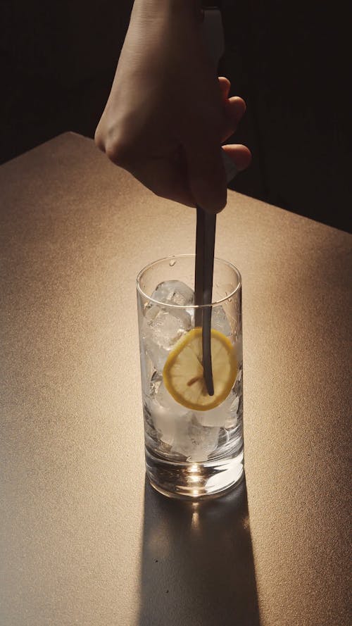 Adding Lemon Slice to Glass with Ice Cubes