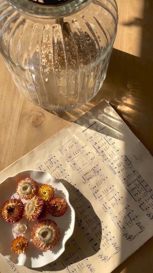 A Music Sheet and a Bowl with Dried Flowers on a Wooden Table