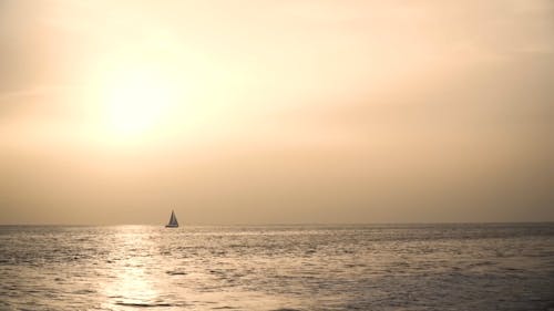 A Sailboat on Calm Sea Waters at Sunset 