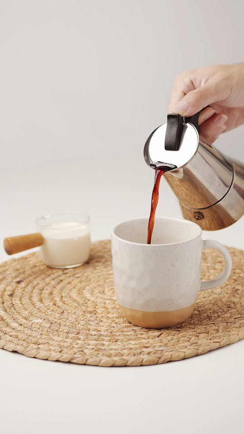 A Person Pouring Coffee into a Ceramic Mug